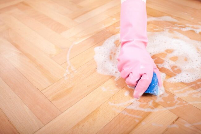 Person scrubbing floor after picking up mouse droppings