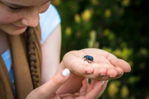 Women holding a small black beetle