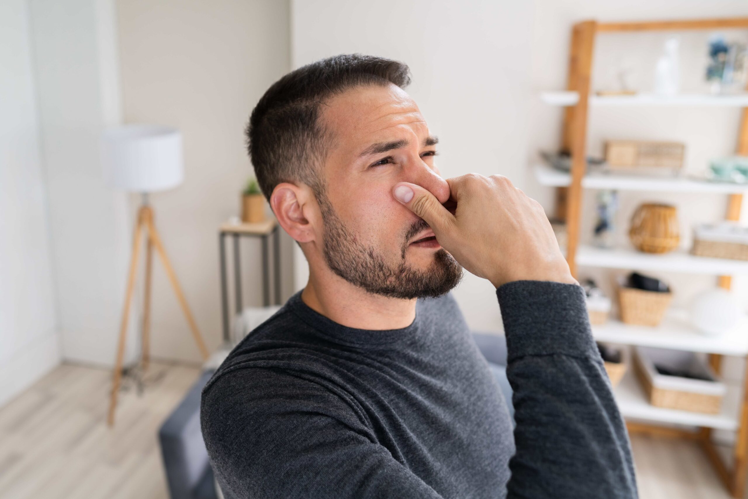 Man plugging his nose because of a smell