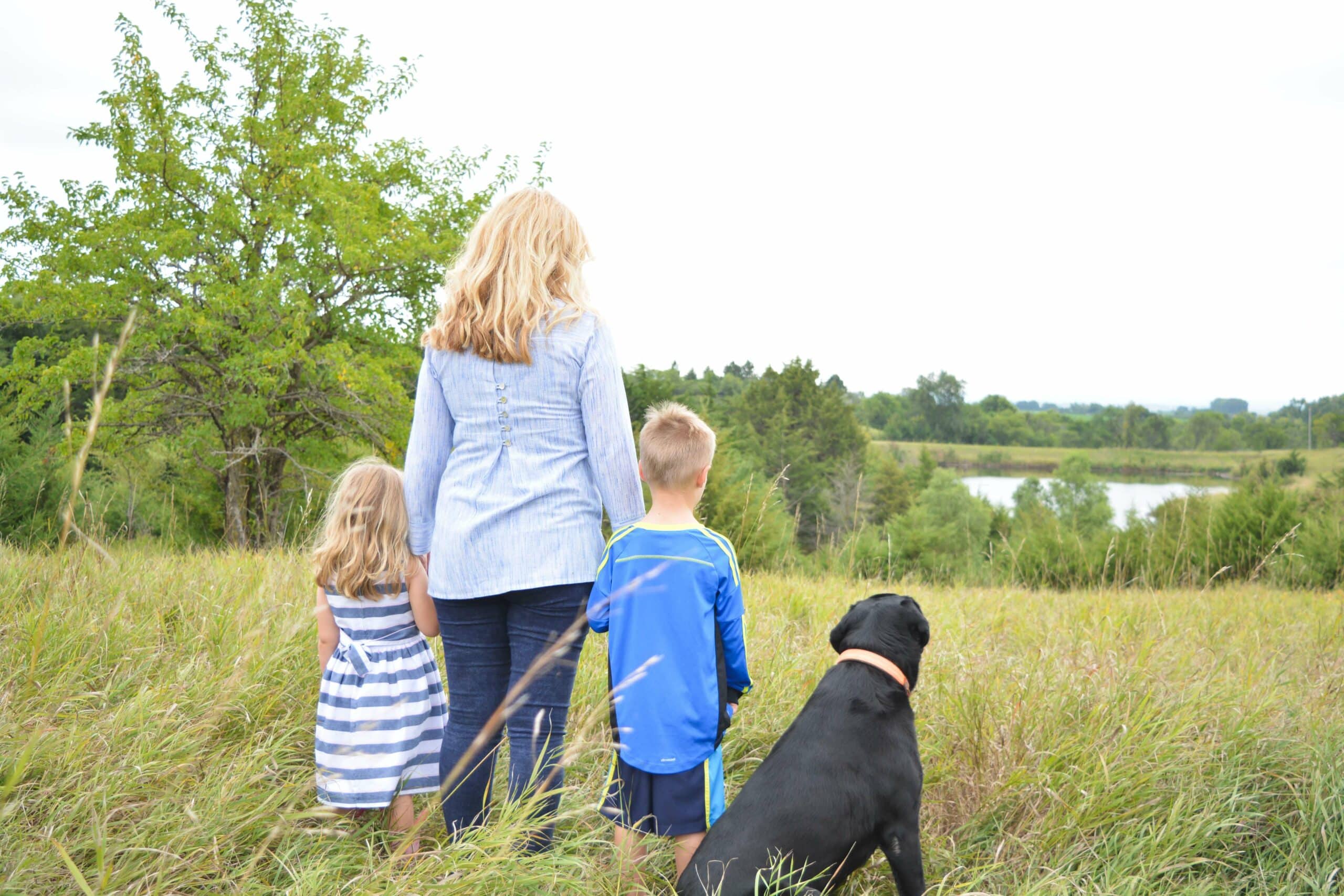 Family and their dog out in a field looking at a lake