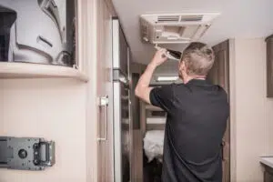 Technician Replacing Air Condition Filter Inside Travel Trailer.