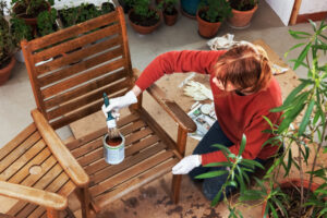 Woman applying a protective coating to a wooden patio chair