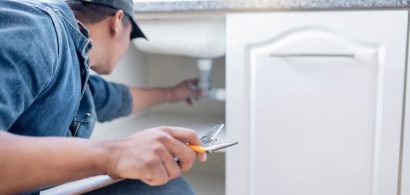 Man_inspecting_pipes_under_sink-1