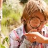 boy outside looking at spider magnifying glass