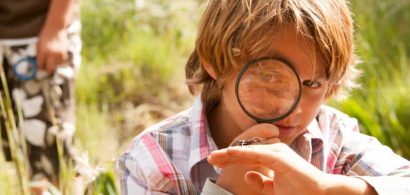 boy outside looking at spider magnifying glass